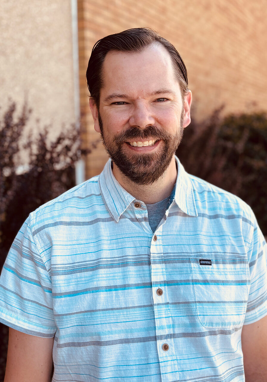 Smiling man in striped shirt outside building